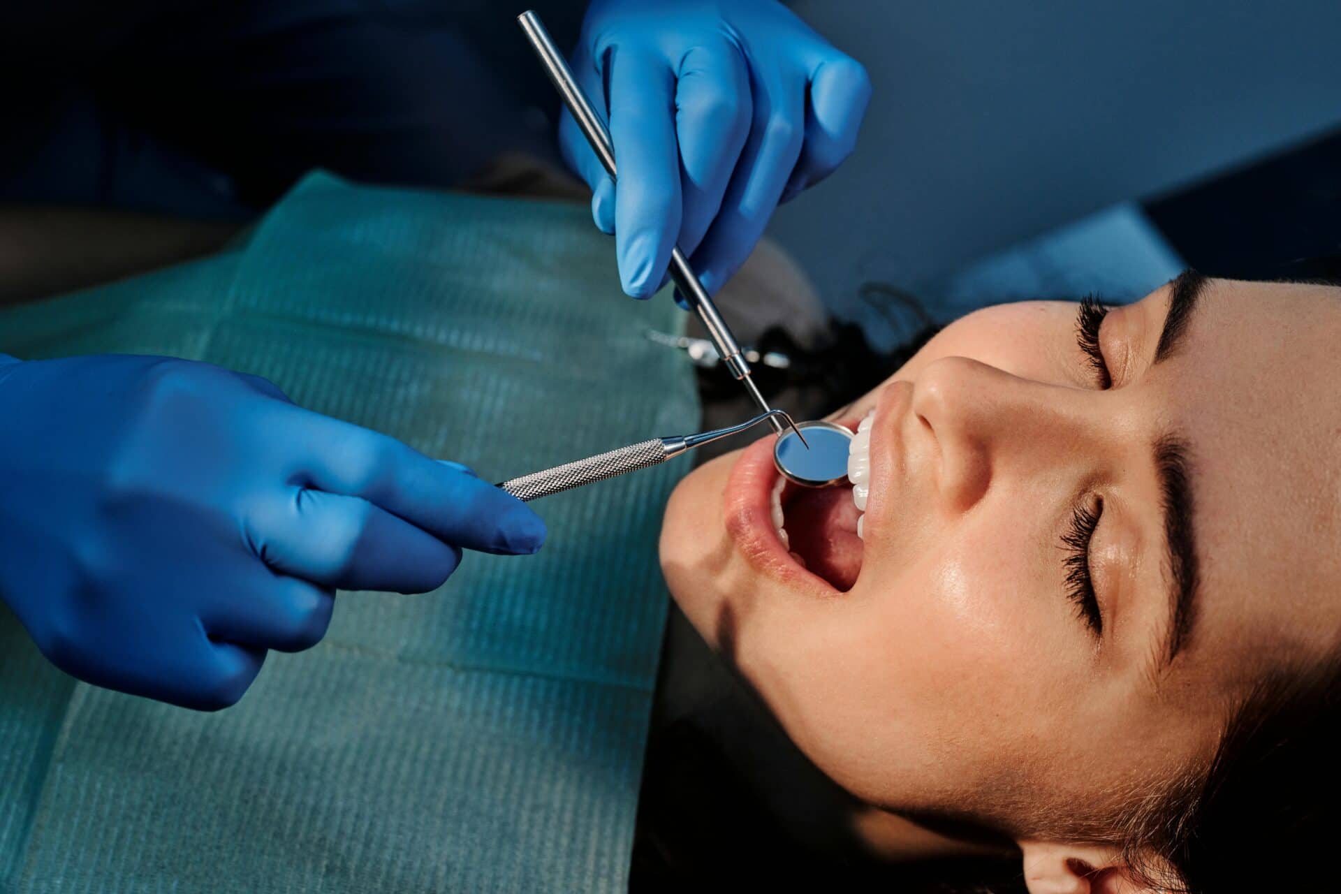 Closeup of a dentist examining a patient's teeth using dental tools.
