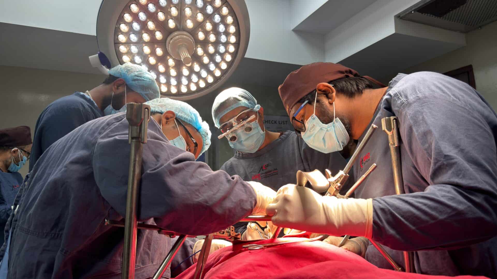 Team of surgeons focused on a surgical operation under bright lights in a hospital operating room.