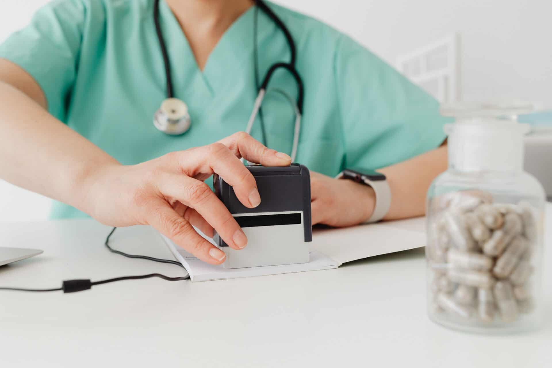 Pharma Jobs 1 Closeup of a doctor stamping a prescription with a bottle of pills on a desk.